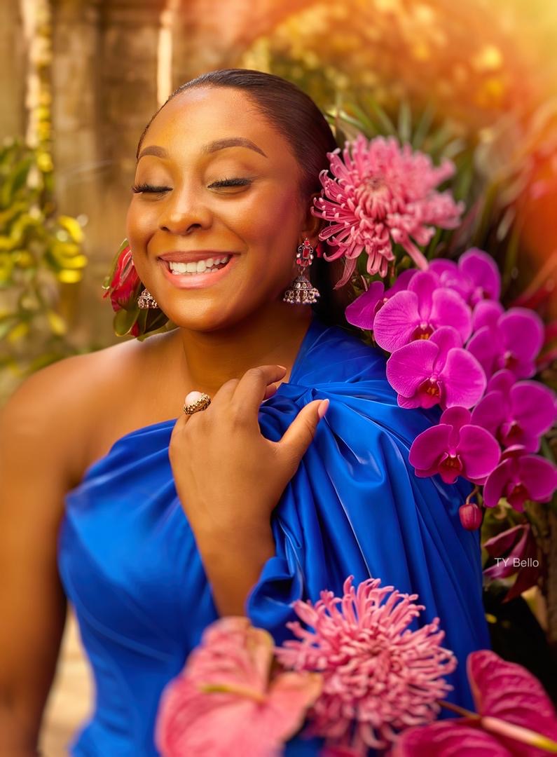 Aisha in a cobalt blue satin dress among pink orchids