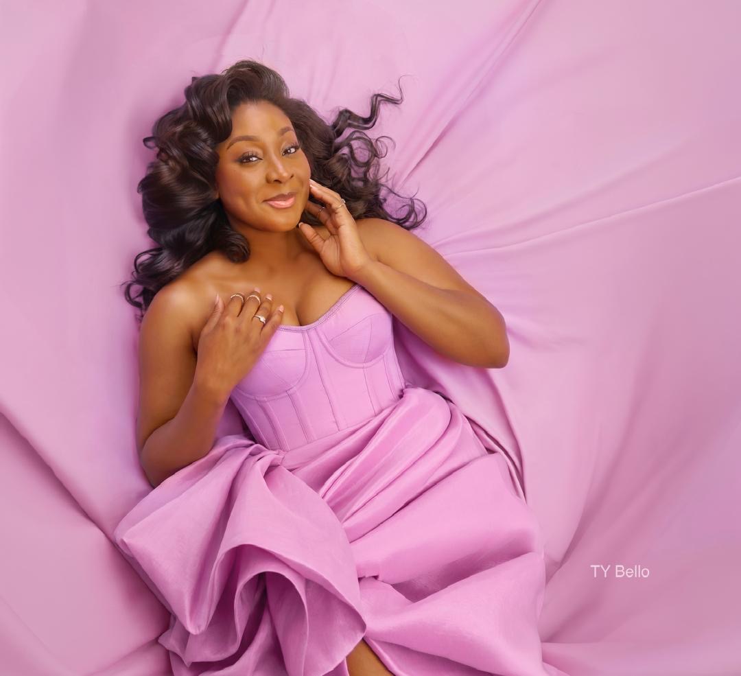 Aisha in a pink corset dress lying on pink silk